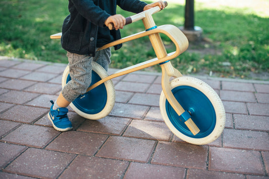 Toddler riding a balance bike outdoors on a paved path