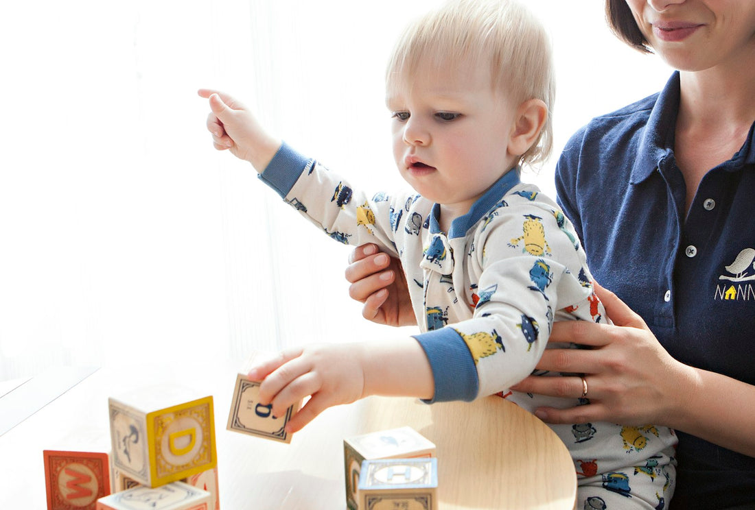 Toddler playing with colorful learning blocks alongside a caregiver