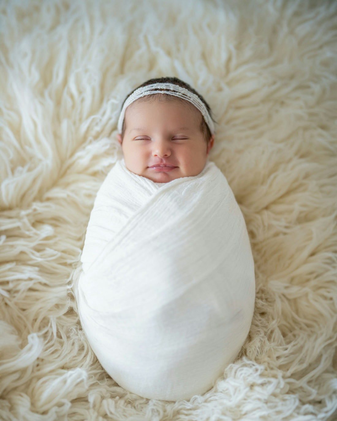 Newborn baby swaddled snugly in a soft white blanket