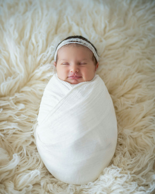 Newborn baby swaddled snugly in a soft white blanket
