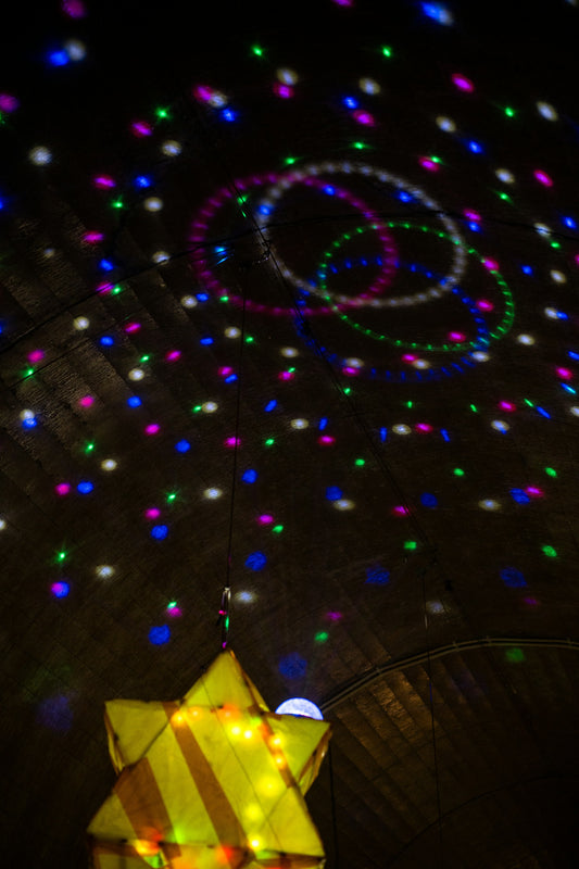Soft colorful star projections glowing on a bedroom ceiling at night