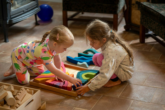 Two young girls playing with colorful wooden stacking blocks