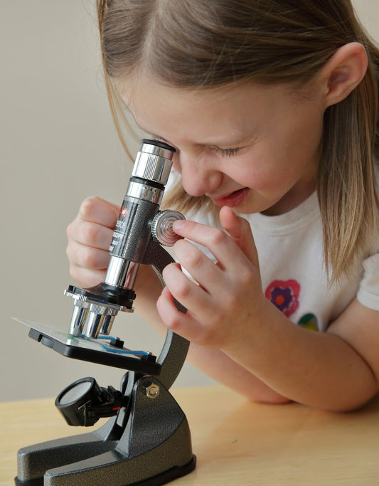 Young girl looking through a kids' microscope